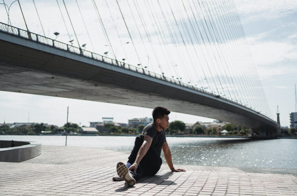 yoga man stretching by a bridge